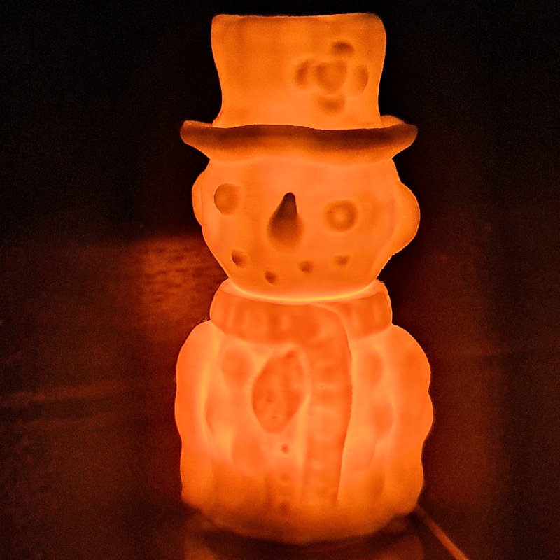 The snowperson illuminated by an LED tealight candle.